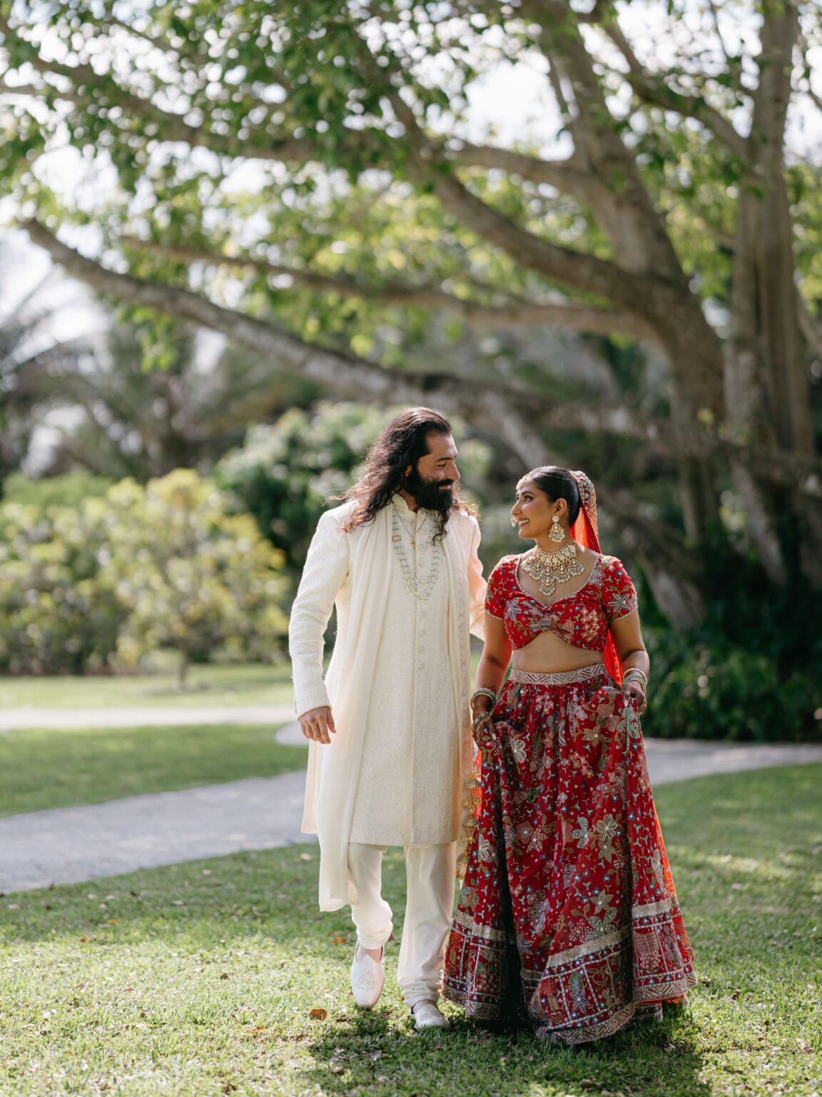 Destination wedding couple in traditional South Asian attire walking through the gardens at Cinco Farm Miami